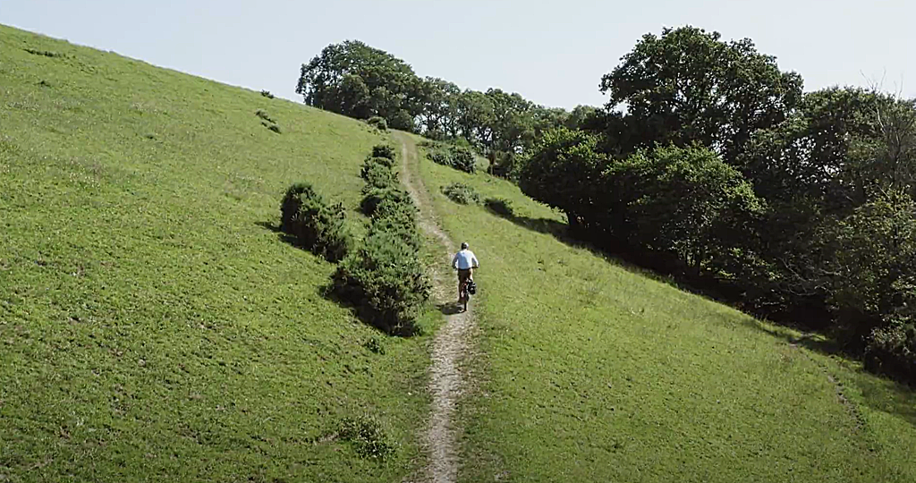 Rider on e-bike demonstrating comfortable, upright riding position on a green hillside
