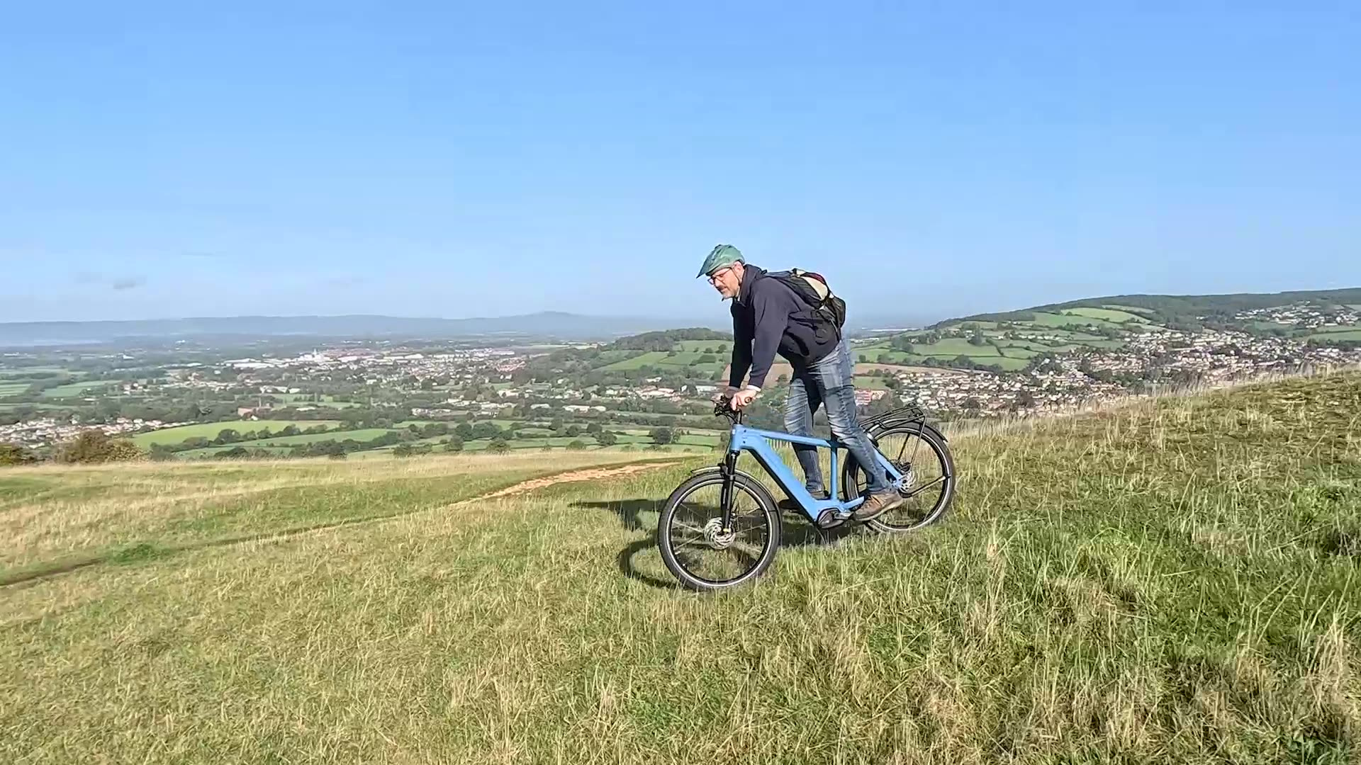 Rider pausing at a hilltop with blue sky and open landscape