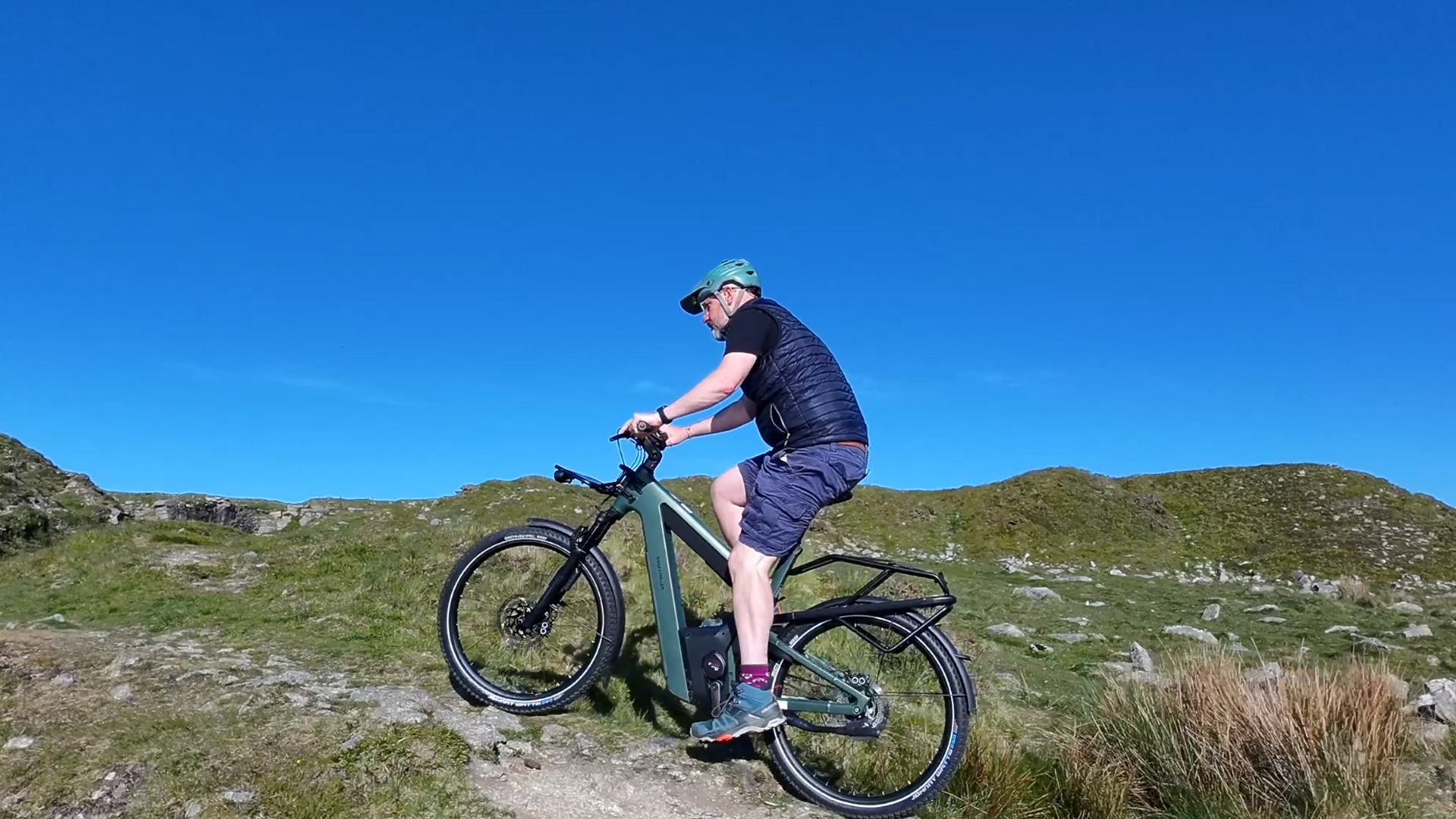 Rider pausing at a hilltop on a summer day with rolling countryside behind