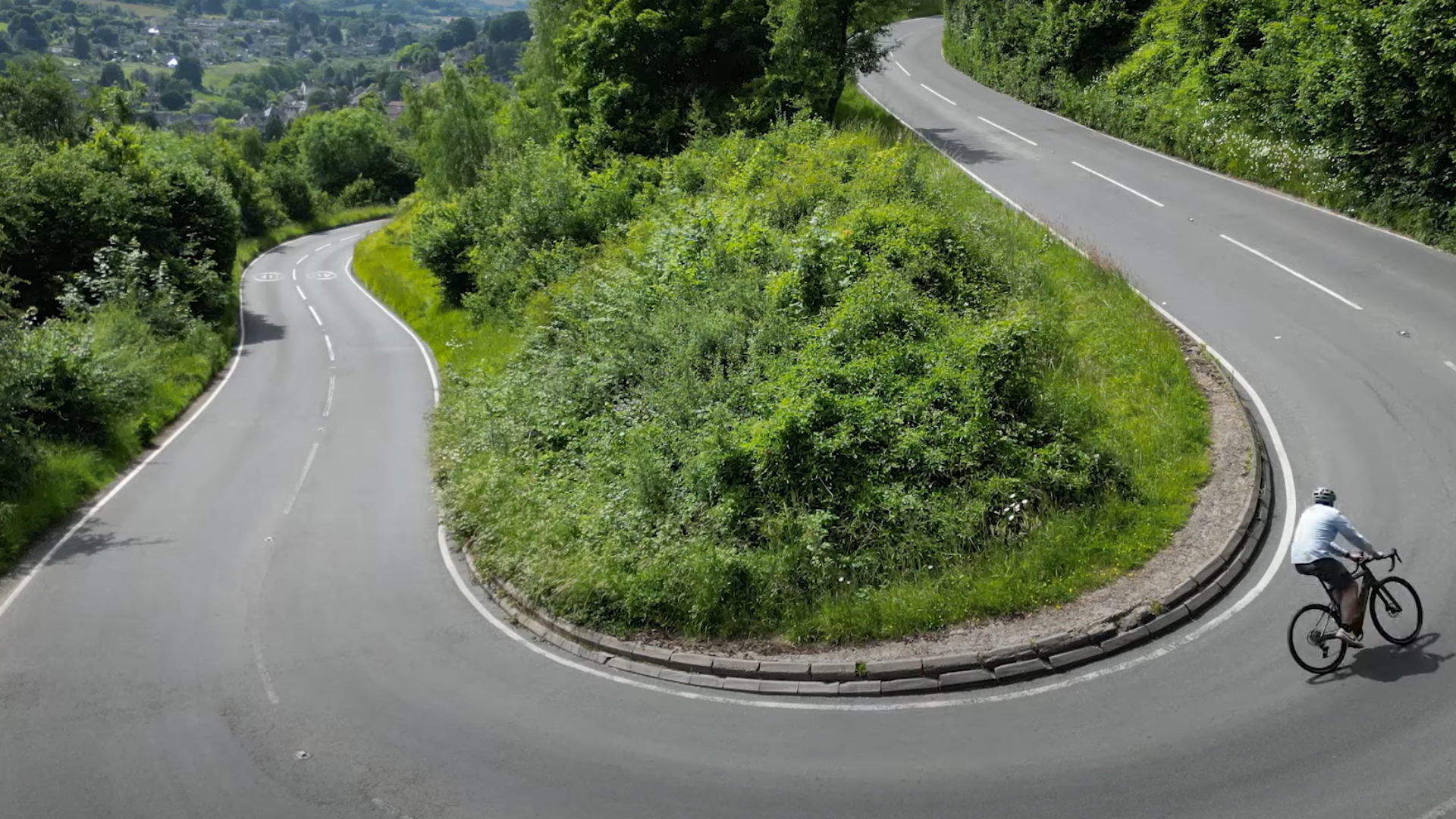 E-bike rider descending a sweeping hairpin bend on a mountain road